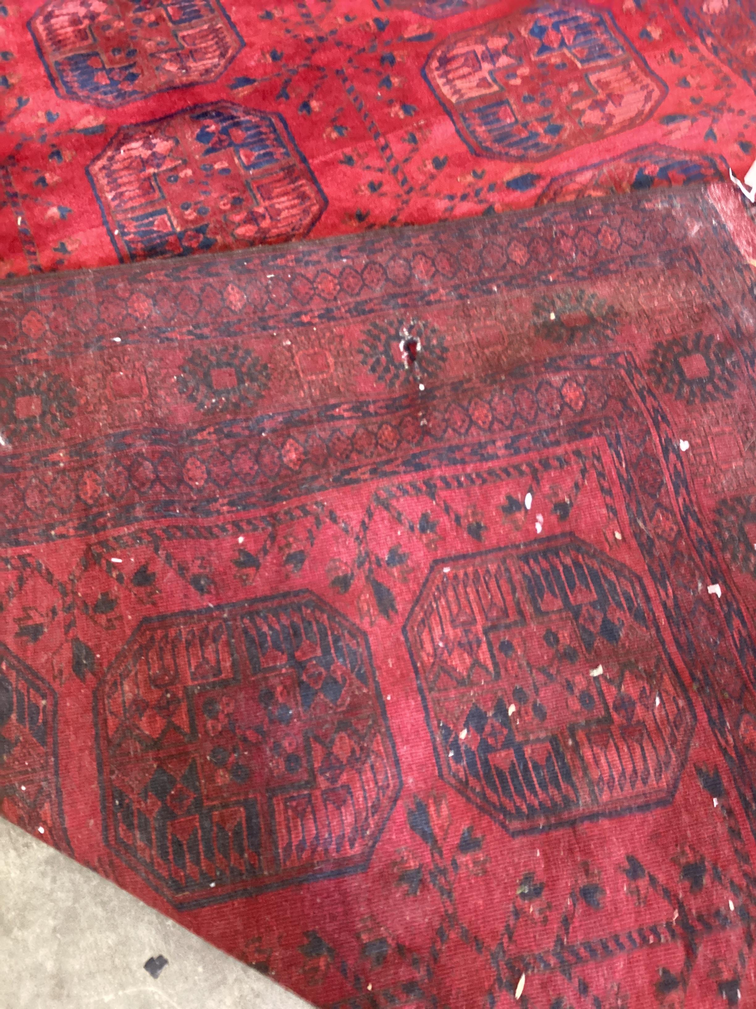 A Bokhara red ground carpet, worn and holed, 286 x 214cm